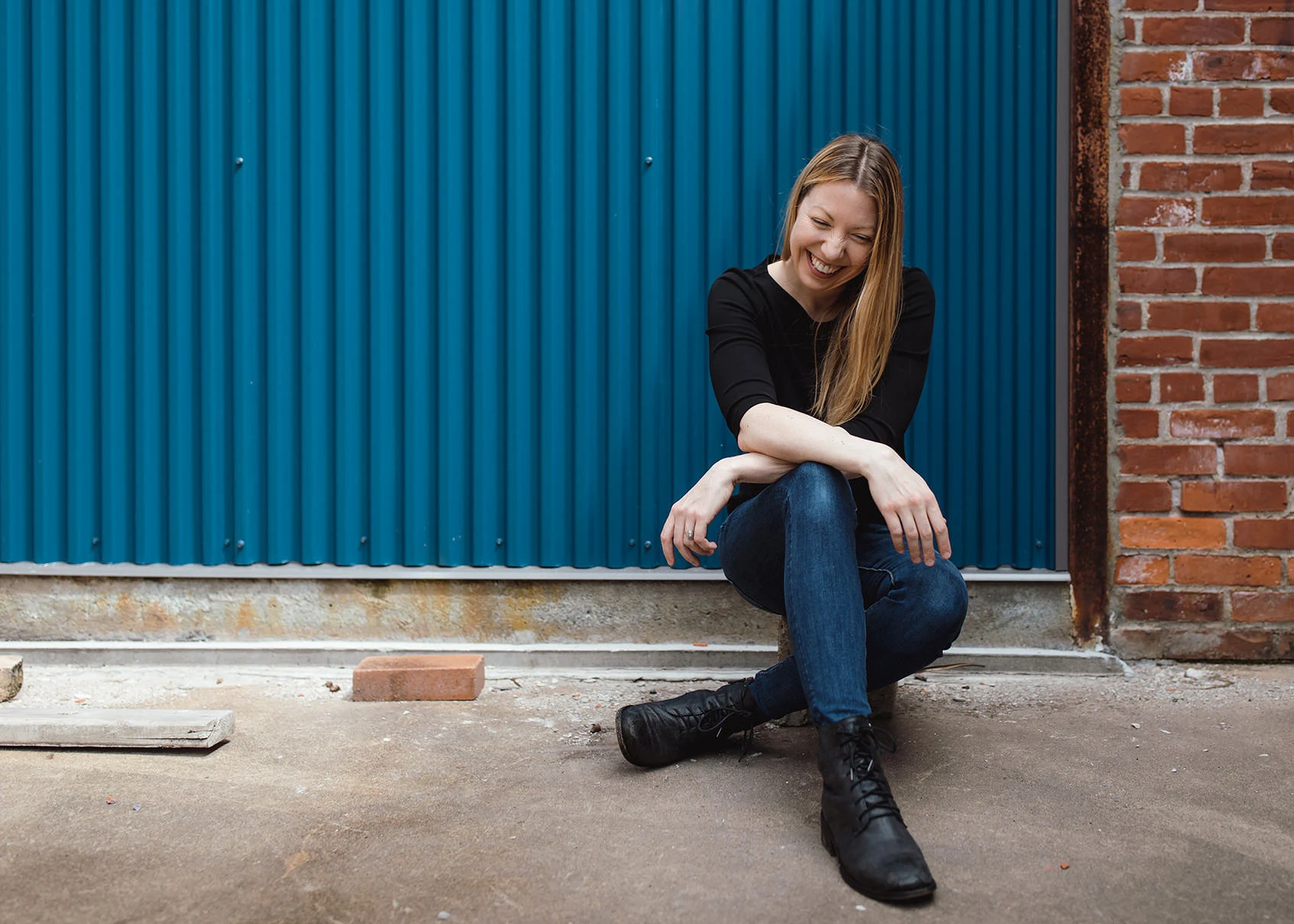 Gina Brocker laughing against a blue wall