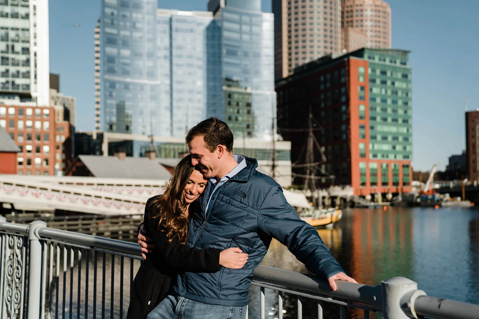 A documentary photograph of a couple cuddling in the seaport during a sunrise engagement session in Boston