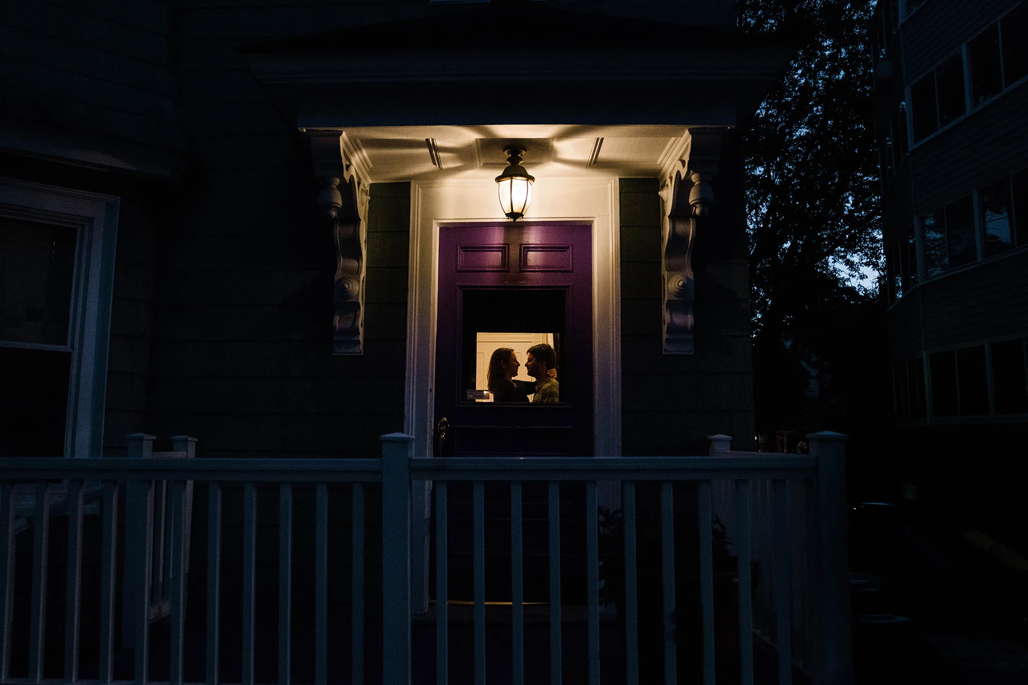 A best of Boston engagement photograph of a couple sharing an intimate moment inside their door after their date night engagement session