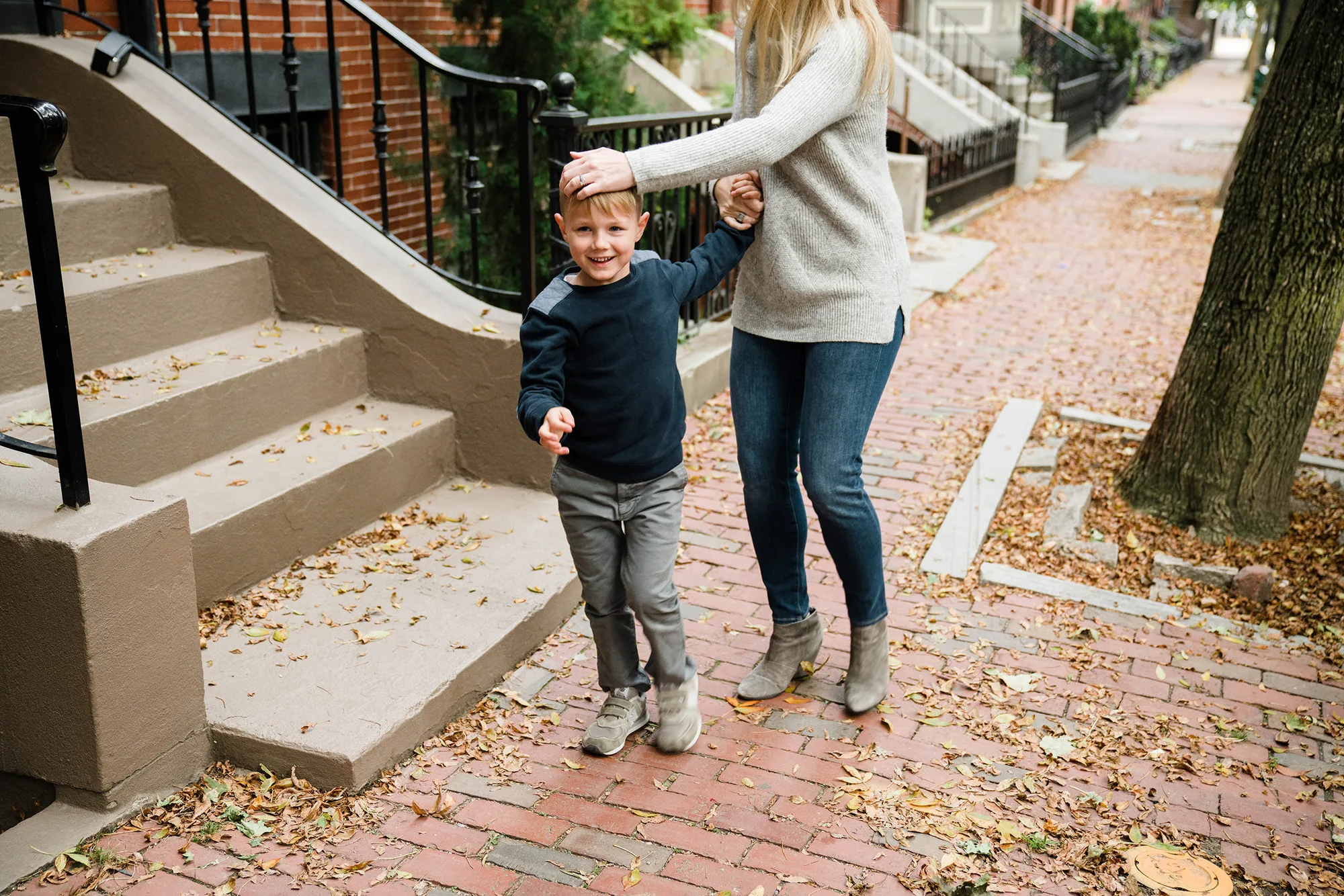 A documentary photograph of a mother and son on the sidewalk during an in home family session in Boston