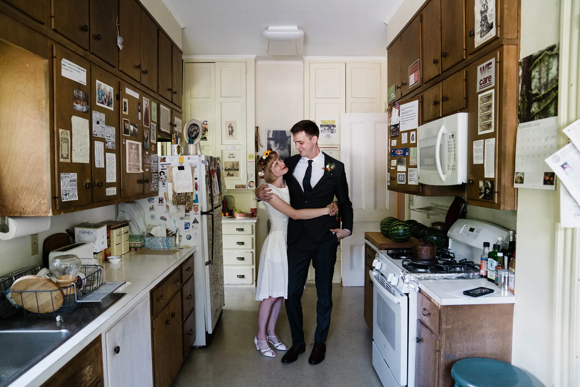 A documentary photograph featured in the best of wedding photography of 2019 of a couple hugging in their kitchen during an in home wedding.