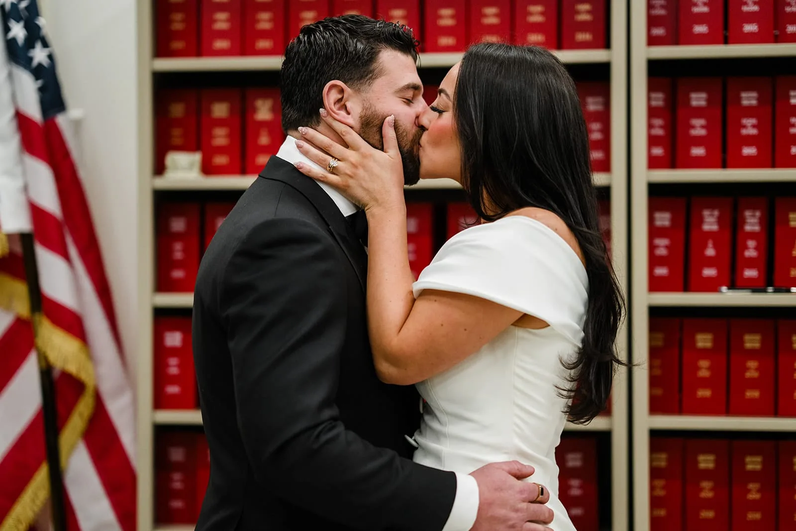 A documentary photograph of a bride and groom kissing during their ceremony at Boston City Hall before their wedding celebration at Mooo.... Seaport.