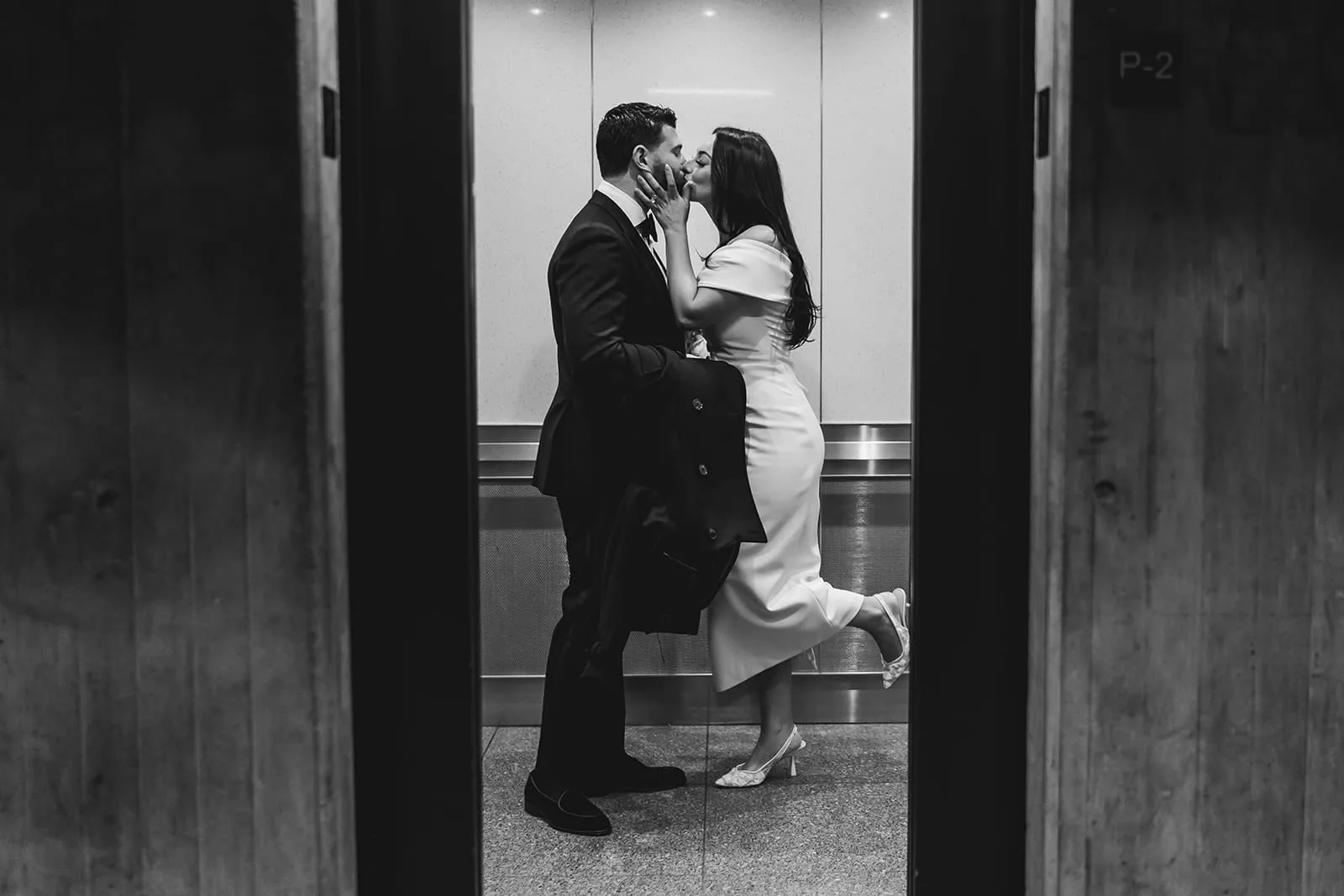 A documentary photograph of a bride and groom kissing in the elevator at Boston City Hall before their wedding celebration at Mooo.... Seaport.
