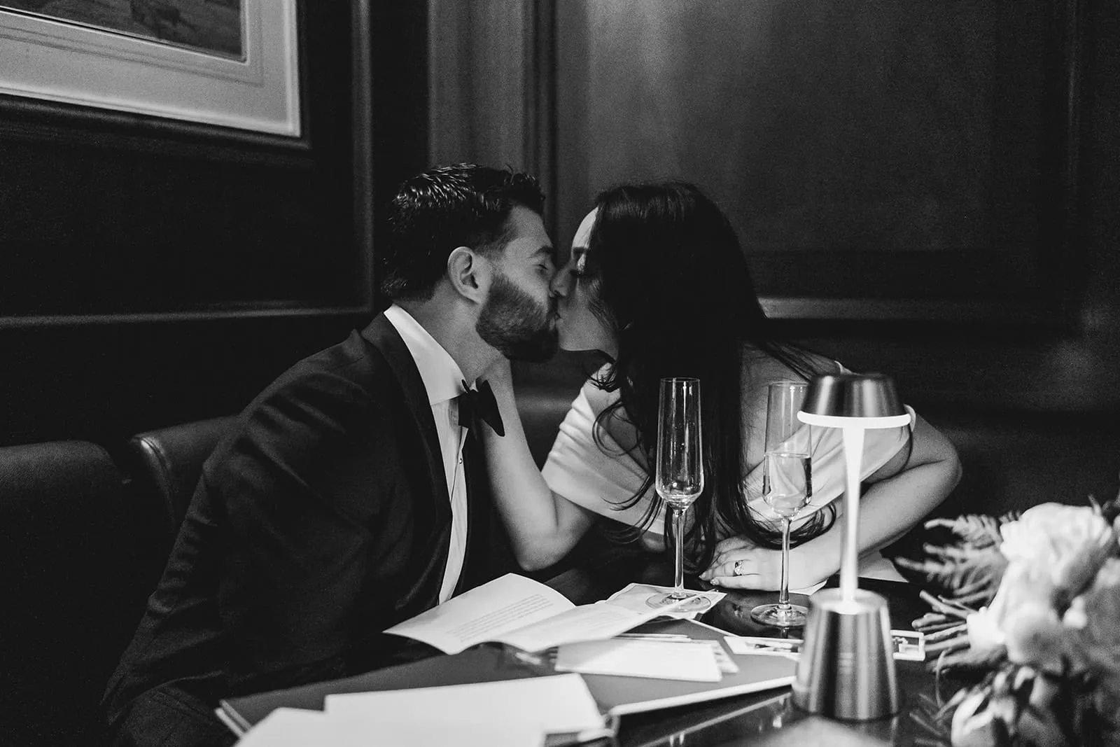 A documentary photograph of a bride and groom kissing at The Dark Bar before their intimate wedding at Mooo.... Seaport.