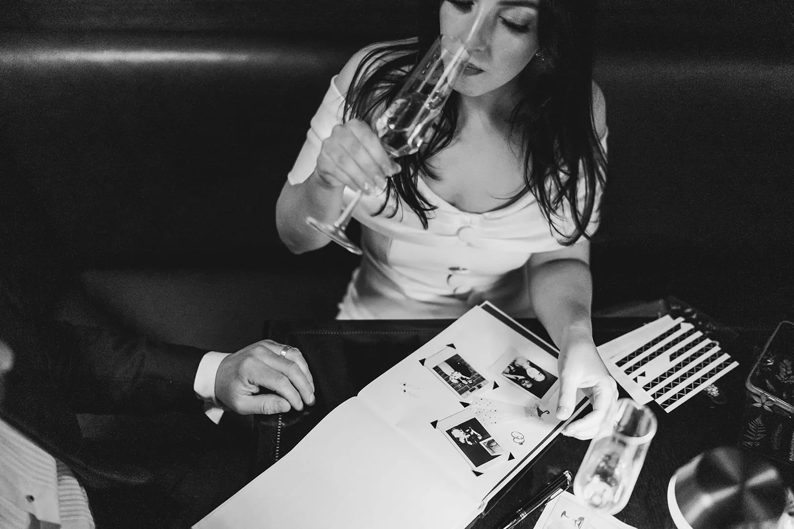 A documentary photograph of a bride and groom creating a guest book at The Dark Bar before their wedding celebration at Mooo.... Seaport.