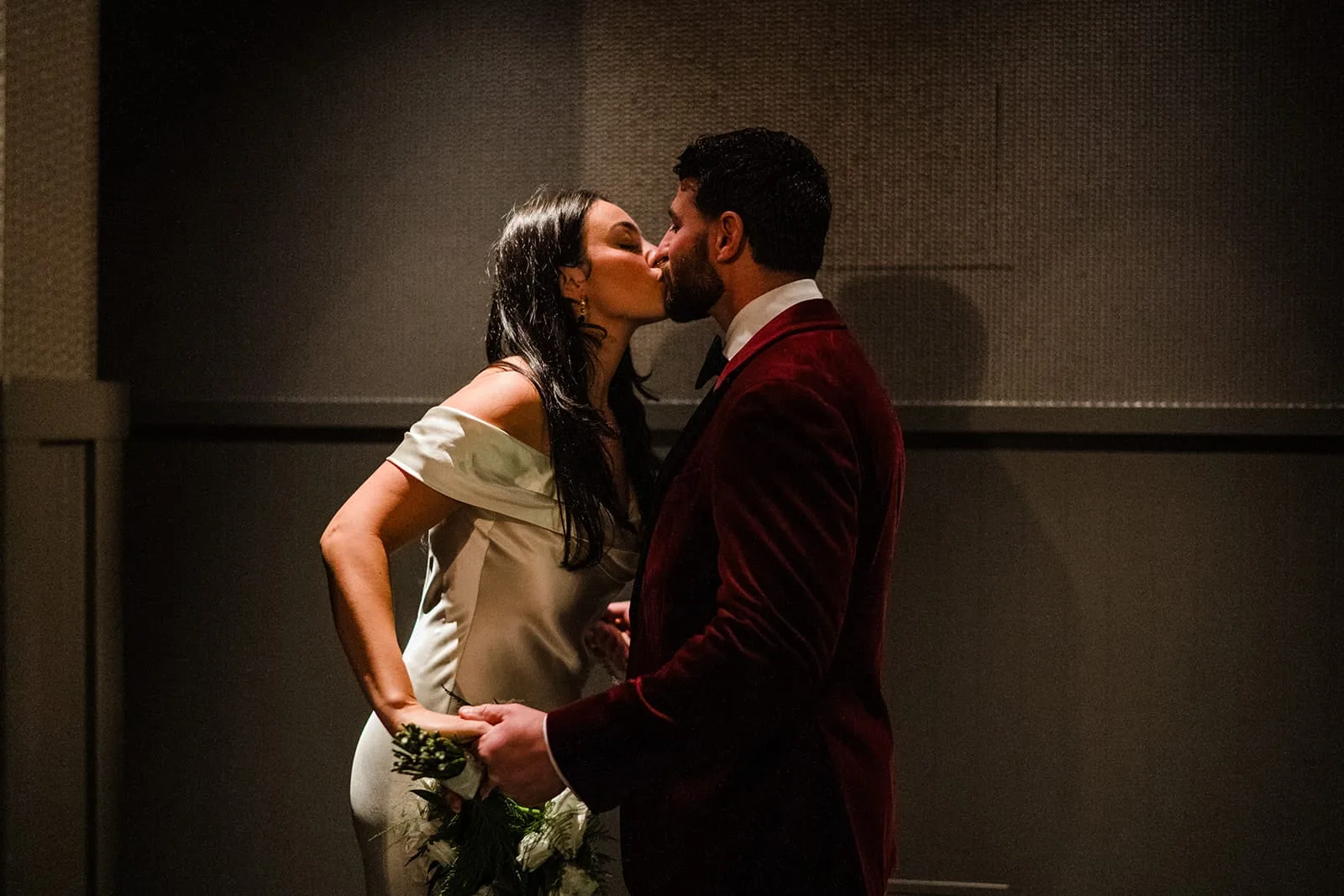 A documentary photograph of a bride and groom kissing before entering their intimate wedding at Mooo.... Seaport.