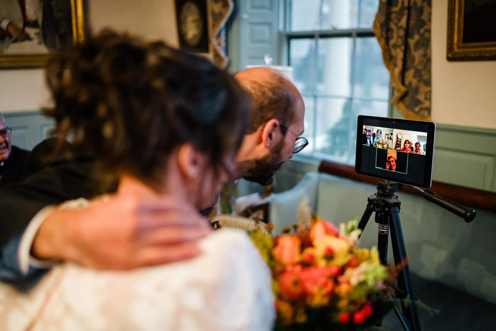 A documentary photograph of bride and groom talking to guest via zoom during their Loring Greenough House Wedding.
