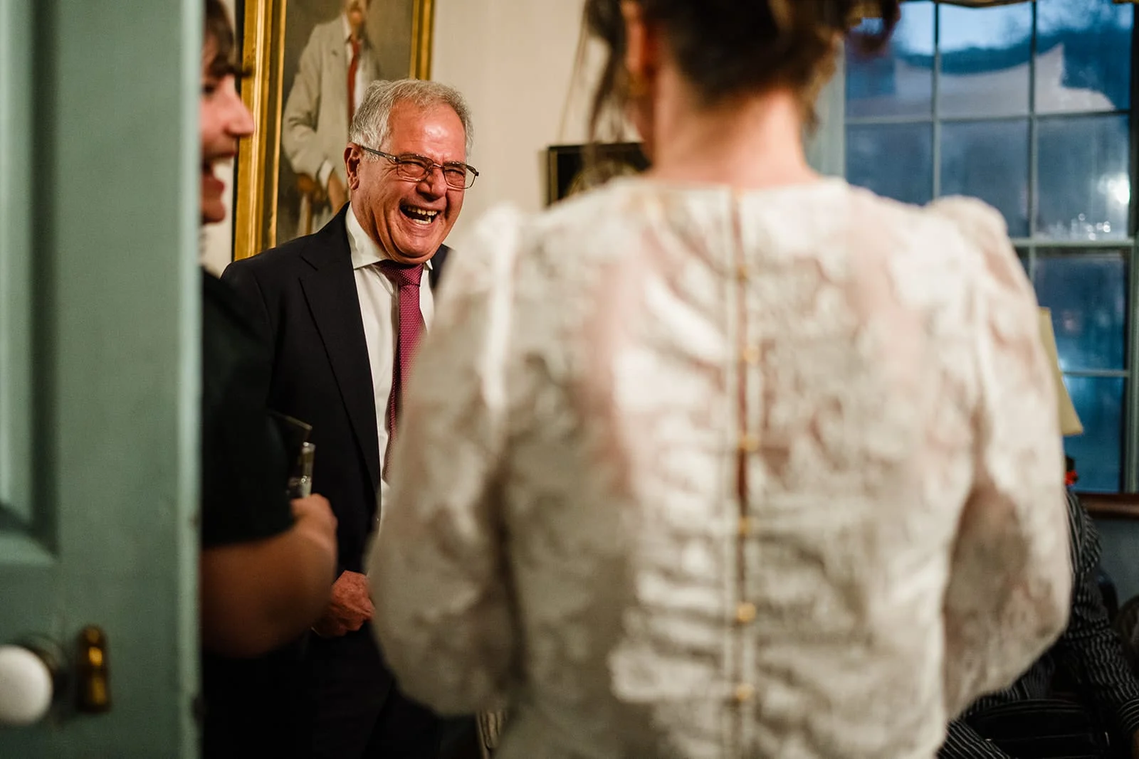 A documentary photograph of the bride talking and laughing with guests during their Loring Greenough House Wedding.