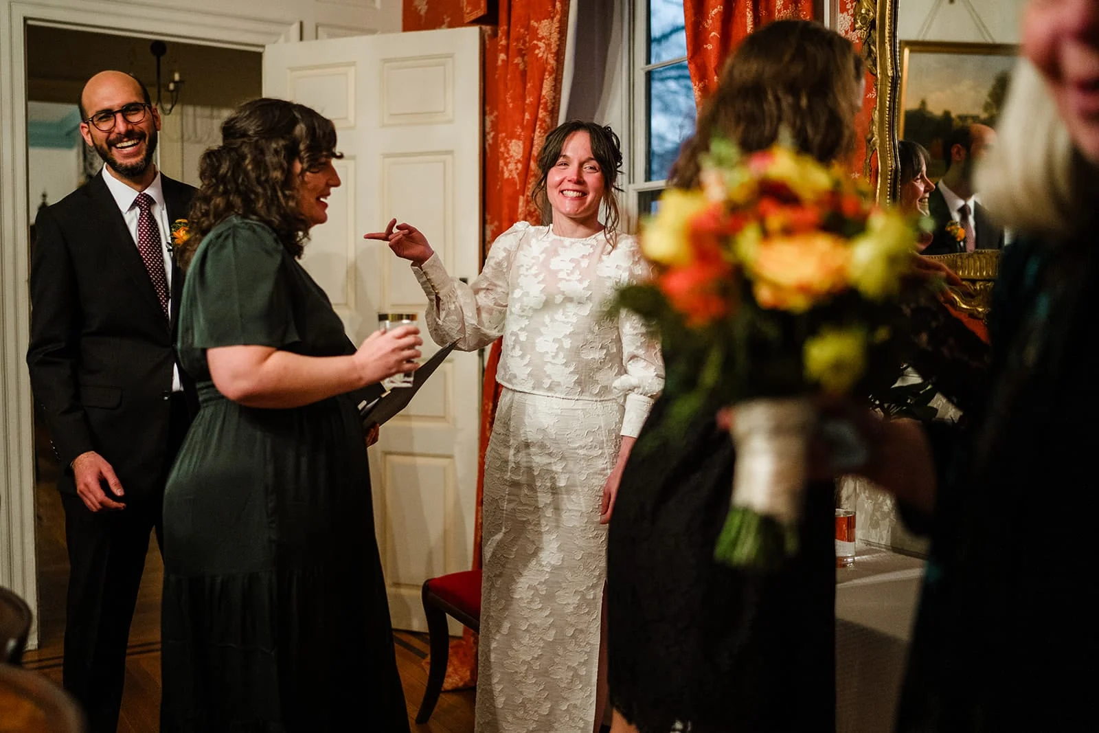 A documentary photograph of the bride talking and laughing with guests during their Loring Greenough House Wedding.