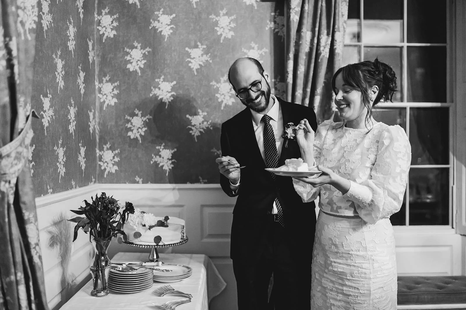 A documentary photograph of a bride and groom eating cake during their Loring Greenough House Wedding.