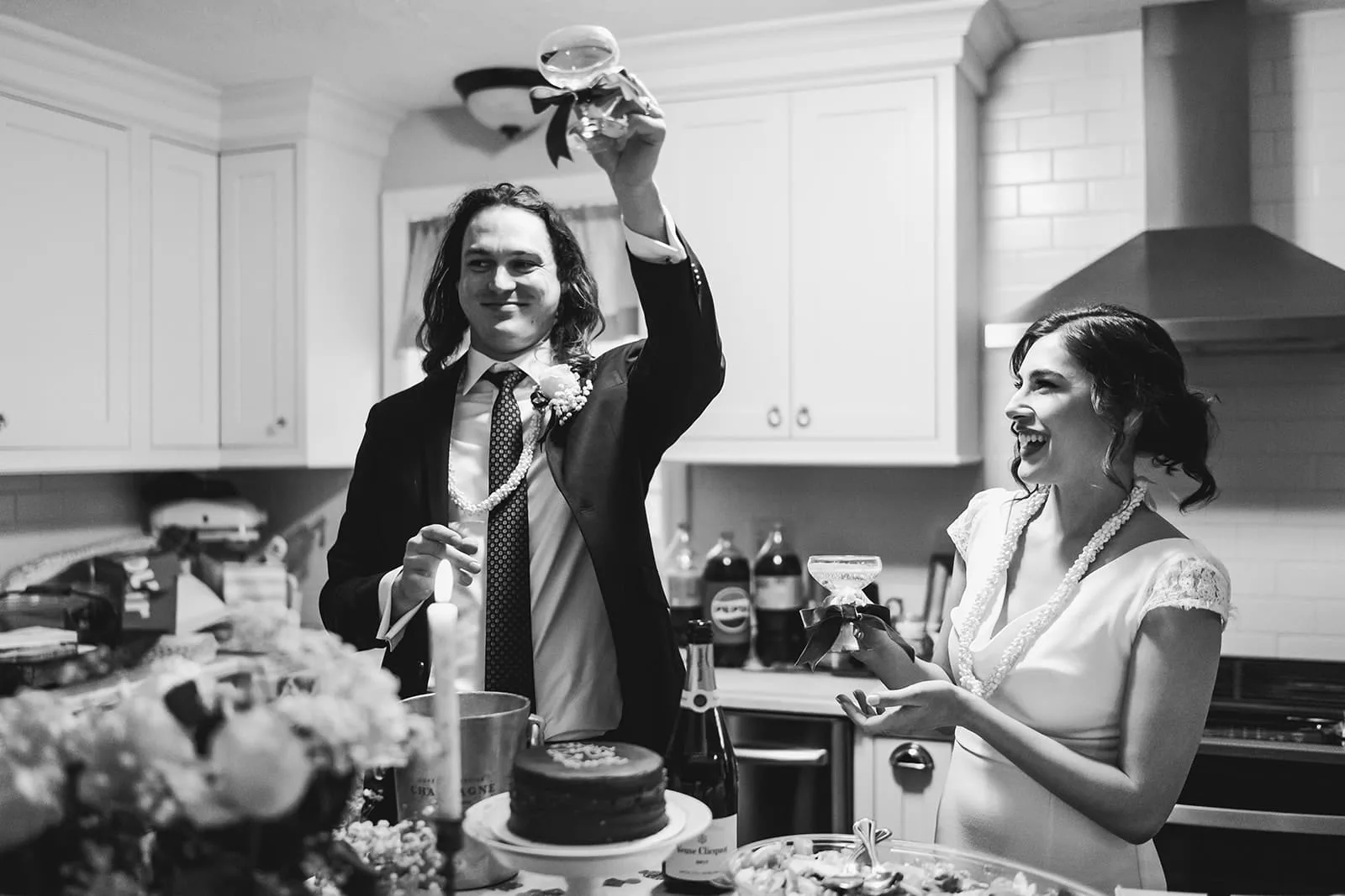 A documentary photograph of a bride and groom laughing in the kitchen during a in home celebration after their intimate Worcester Art Museum Wedding ceremony