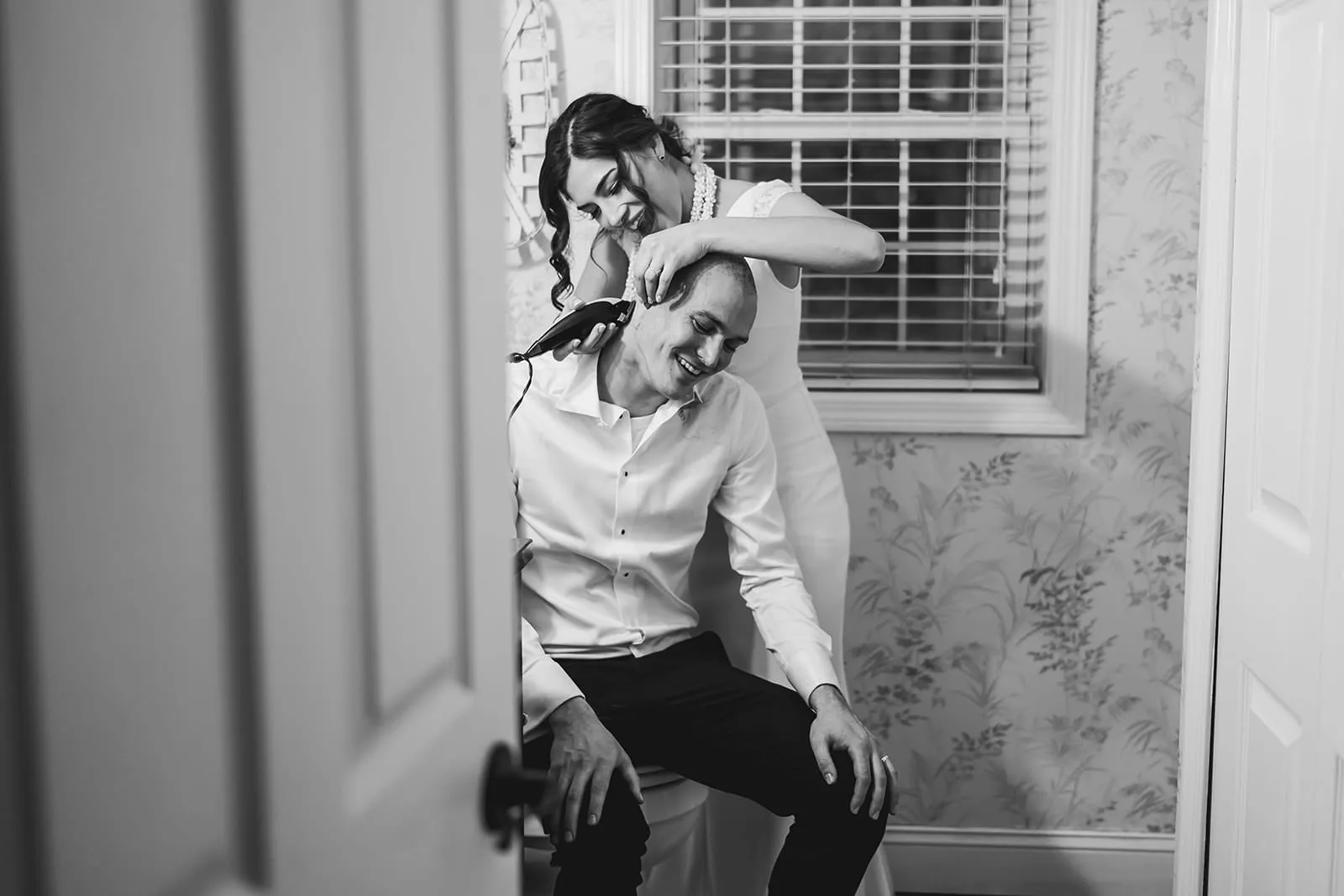 A documentary photograph of a bride shaving a groom's head before cancer treatment during a in home celebration after their intimate Worcester Art Museum Wedding ceremony