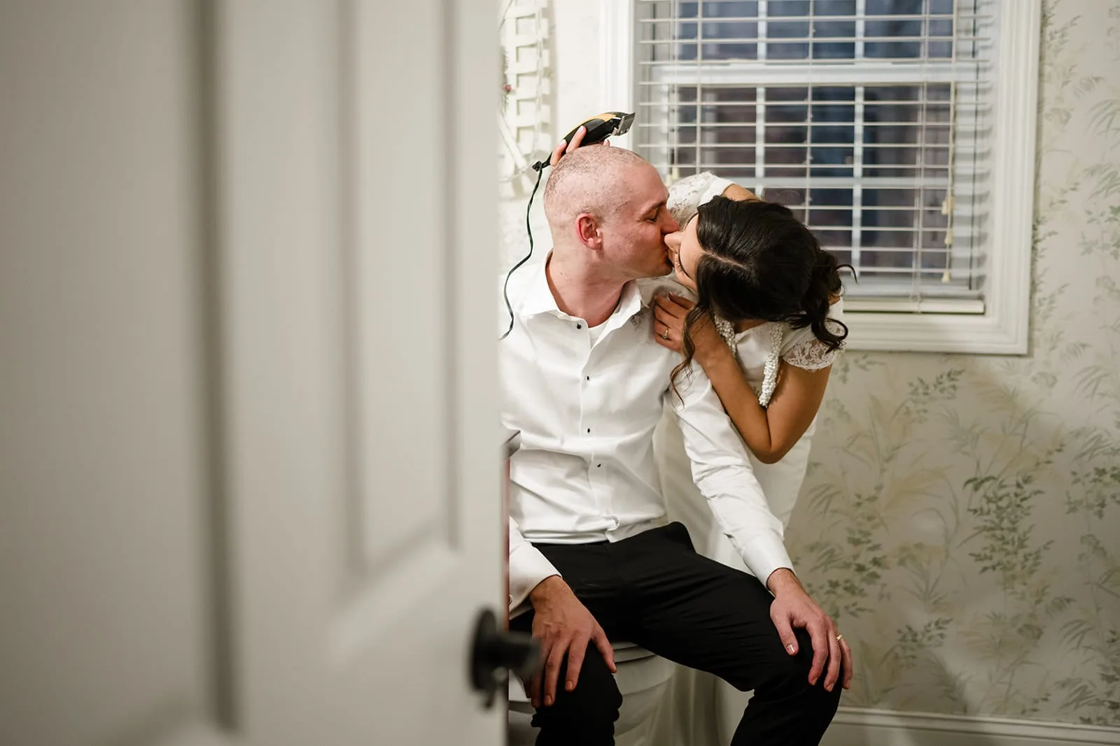 A documentary photograph of a bride shaving a groom's head before cancer treatment during a in home celebration after their intimate Worcester Art Museum Wedding ceremony