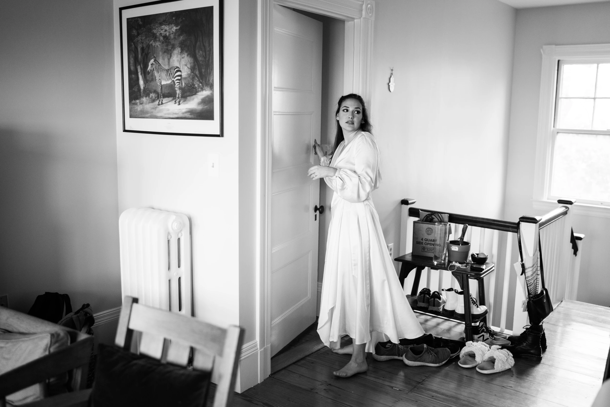 The bride in a robe standing in a bright room