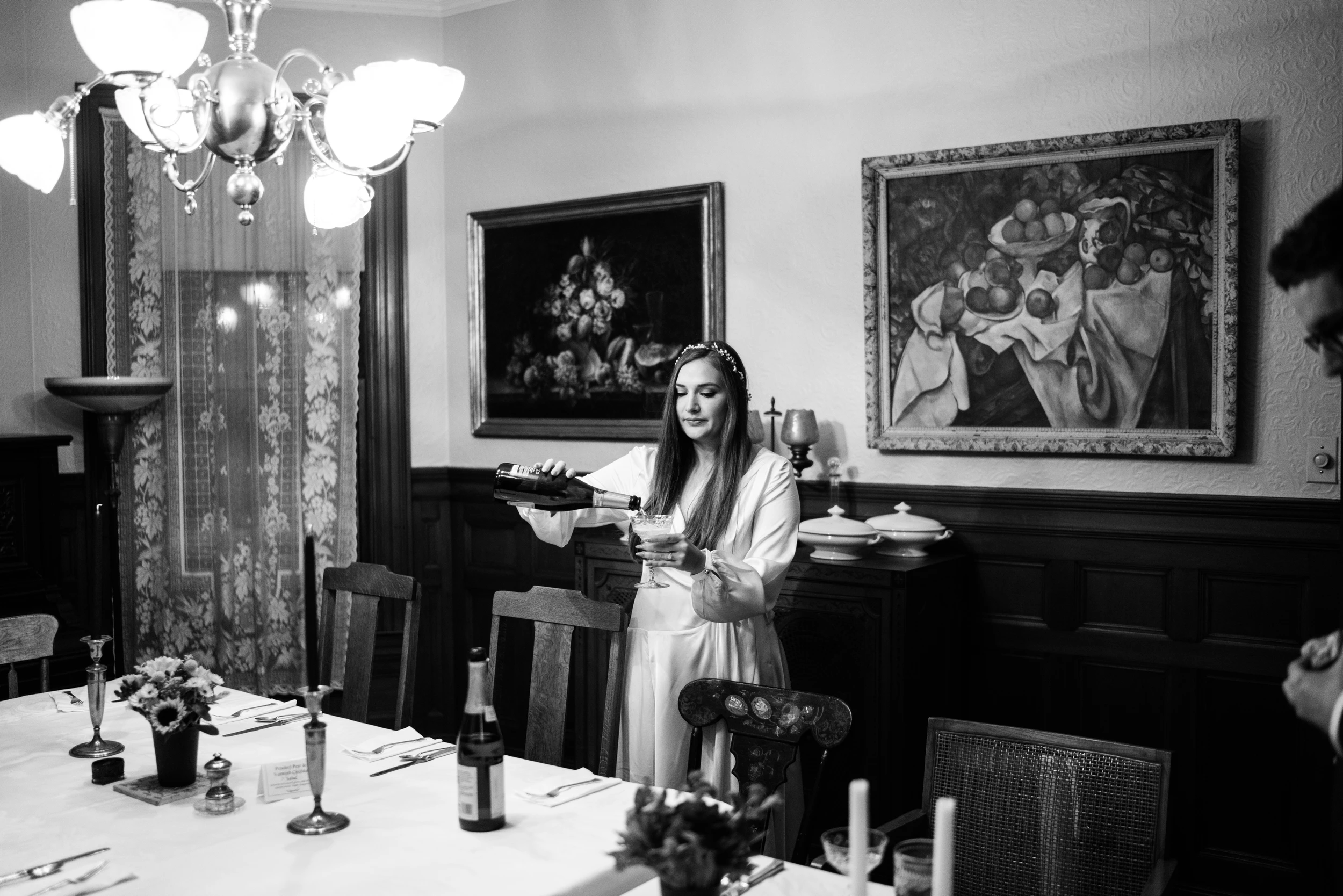 The bride in a dining room under a chandelier and two paintings