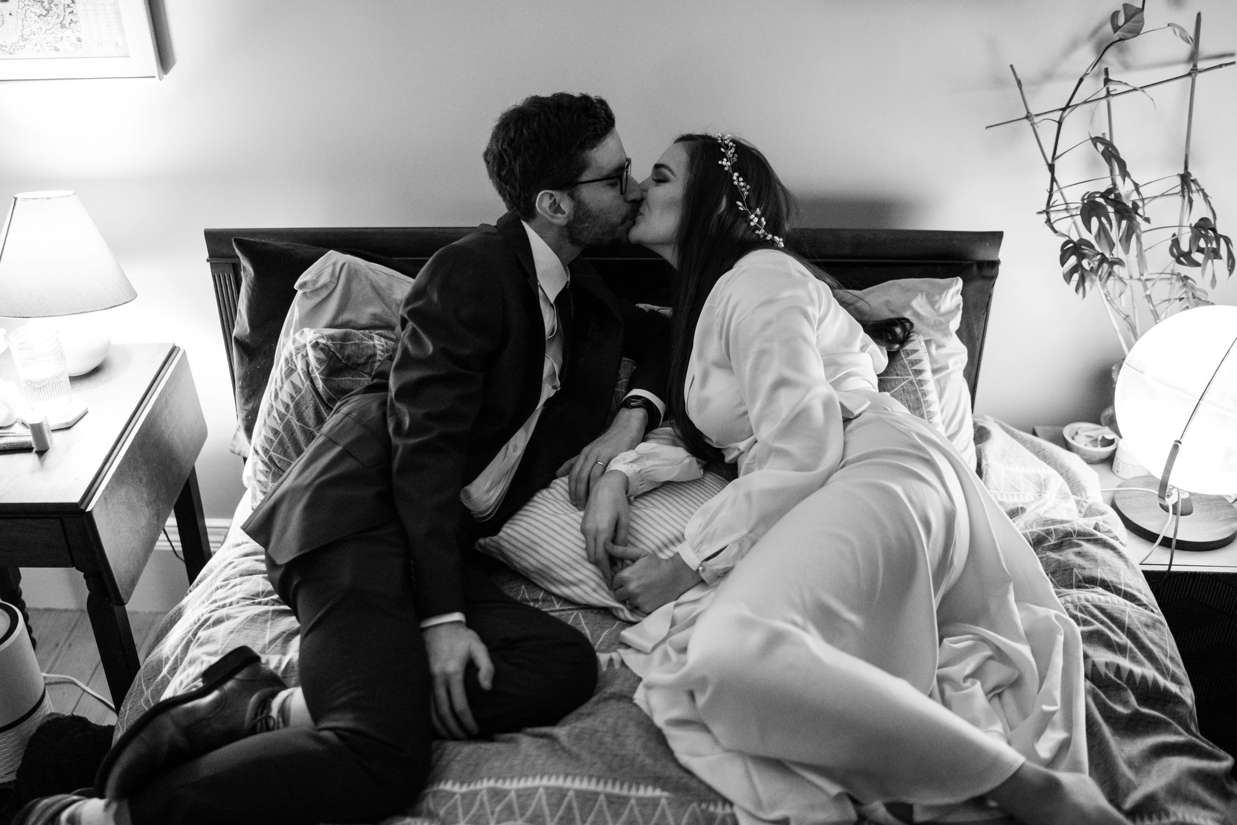 The couple kissing on a bed, her dress spread around them