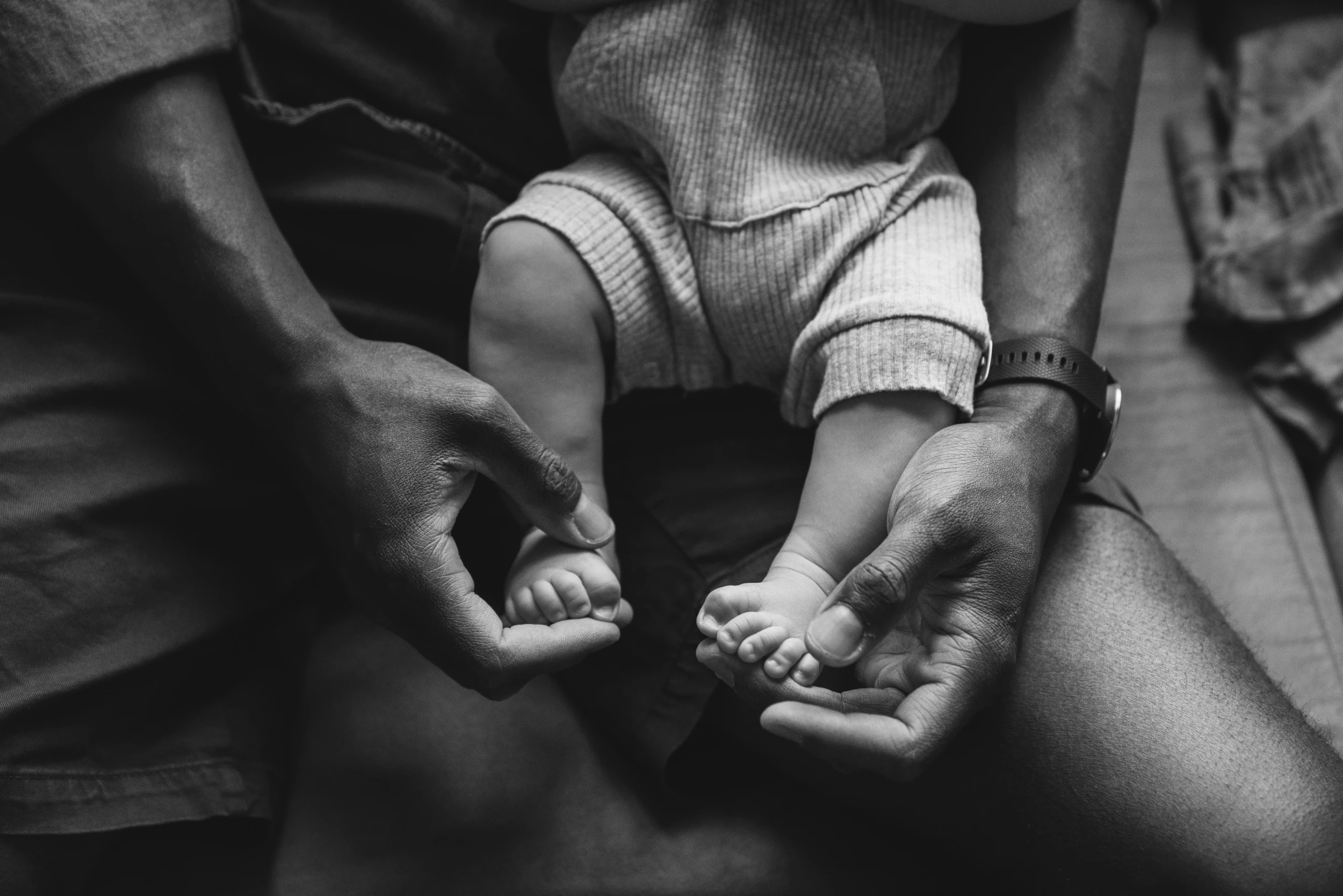 Close-up of a parent's hands cradling a baby's bare feet