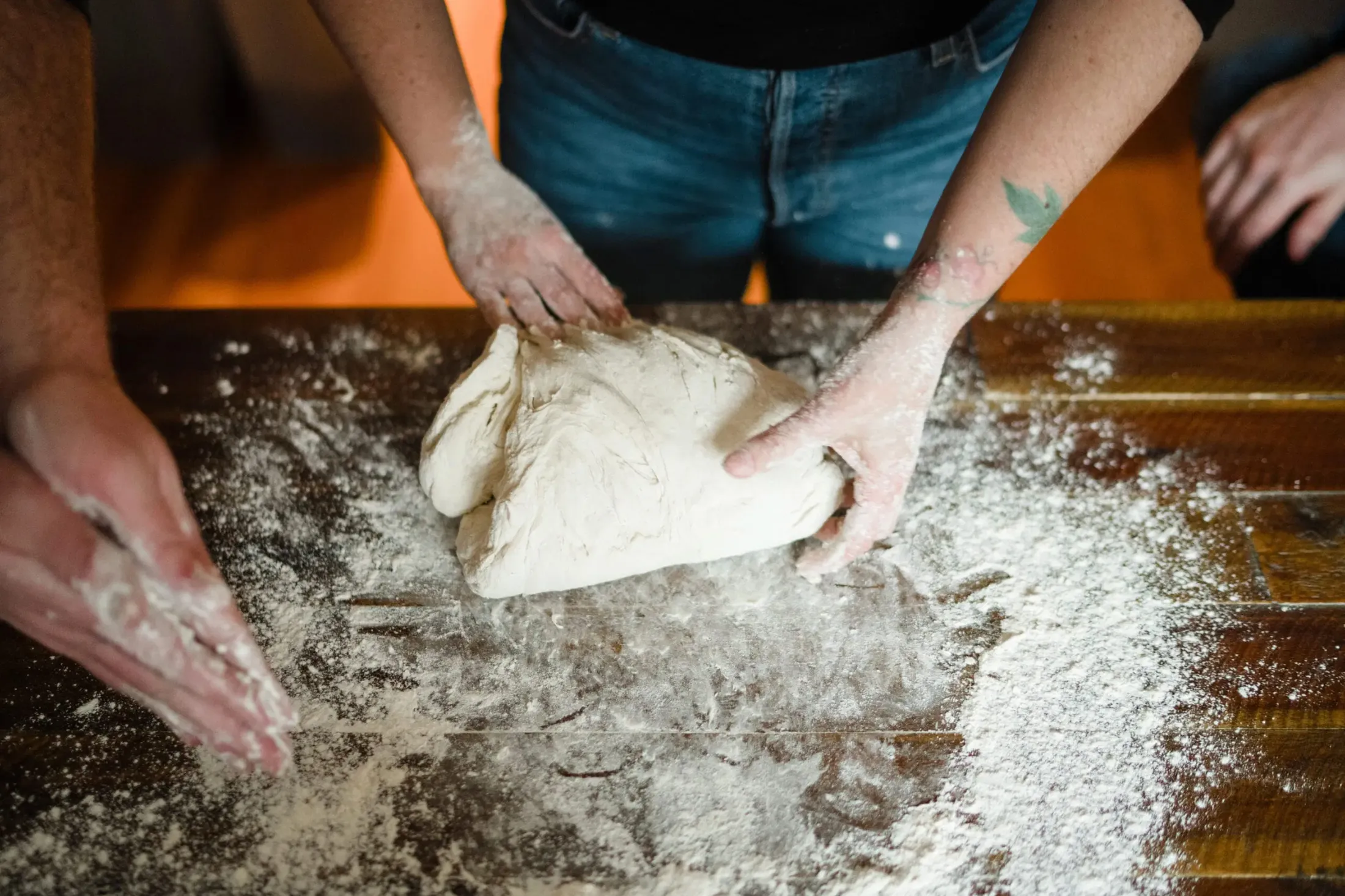 Hands kneading dough on a floured wooden table