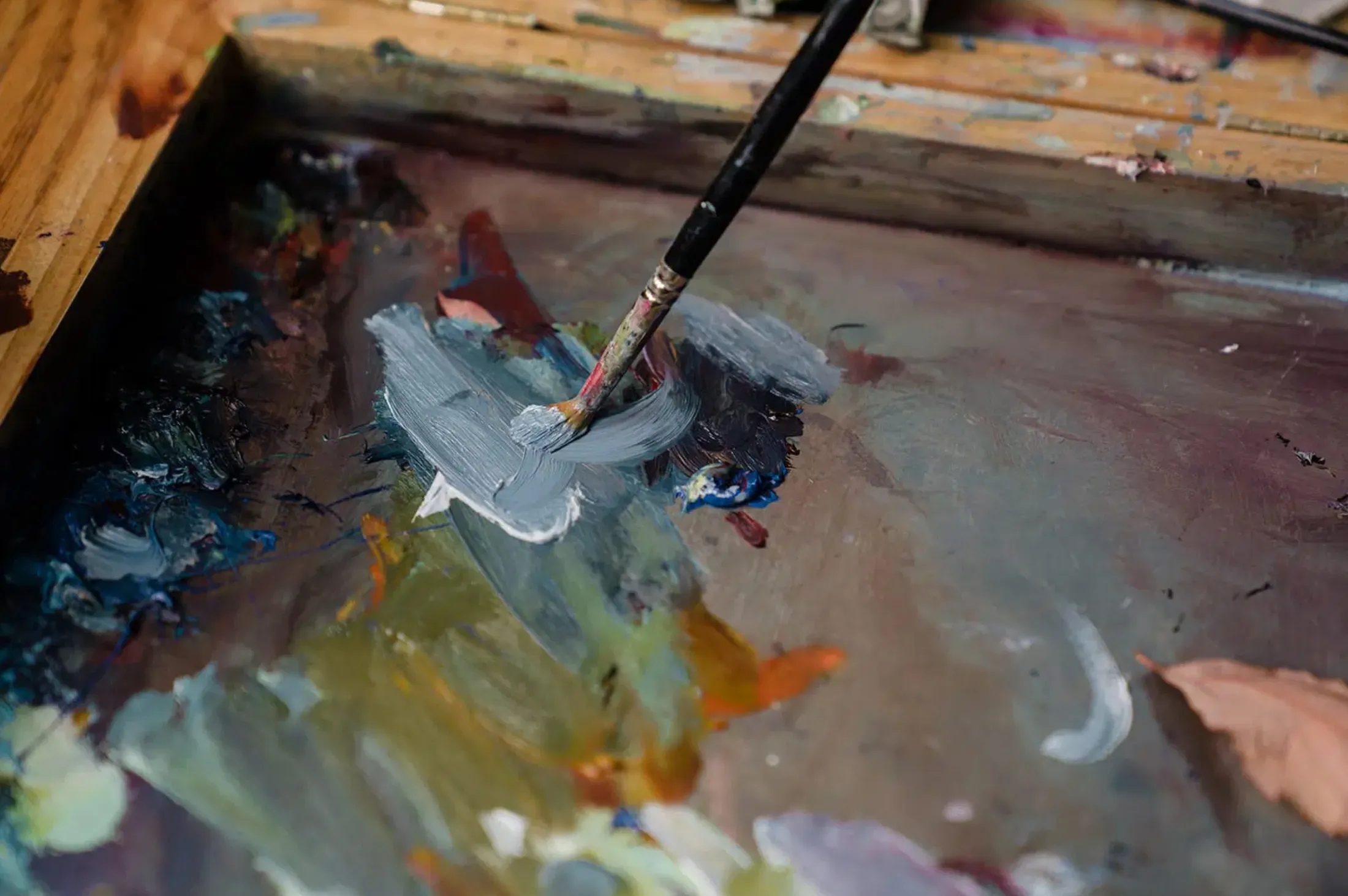 Brush mixing paint on a crowded palette