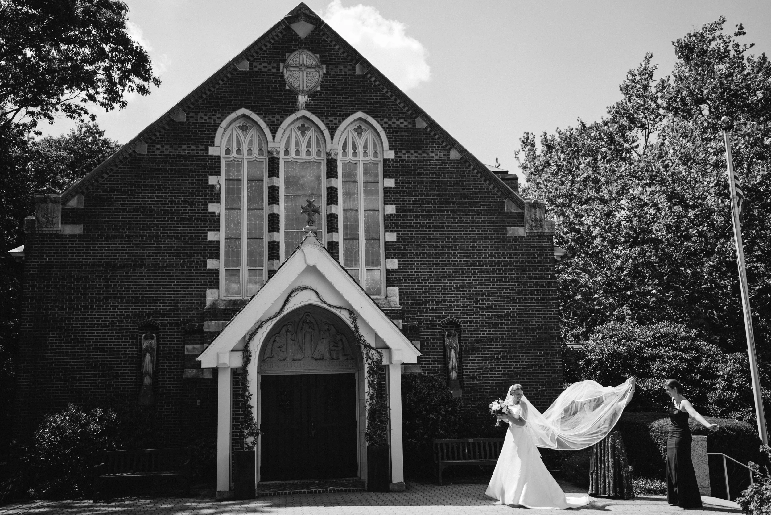 The bride's veil lifting in the wind outside a brick chapel