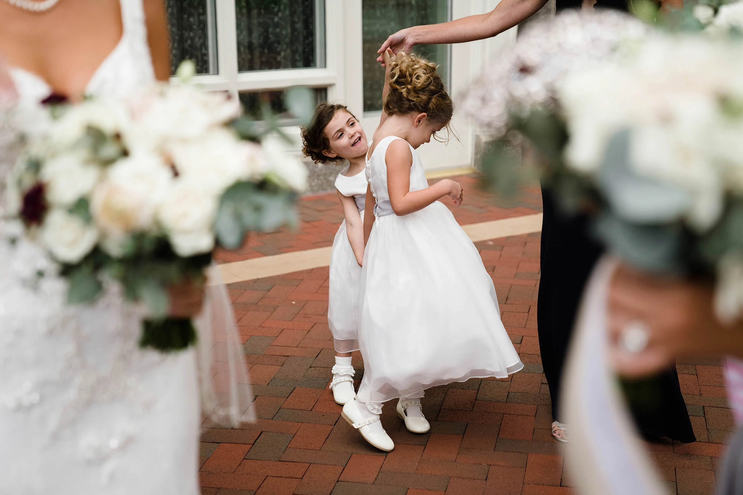 A flower girl spinning in a white dress between bouquets