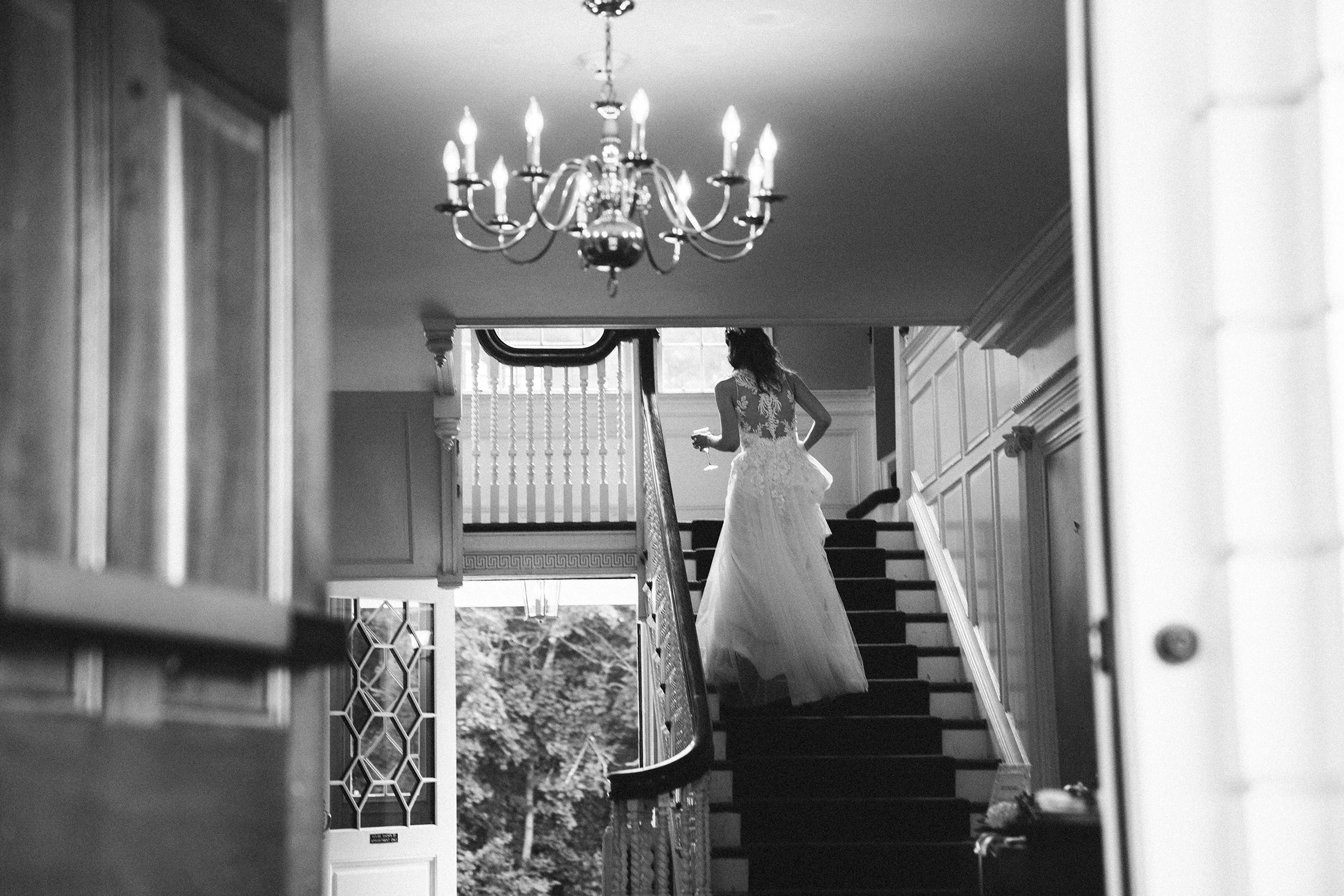 The bride walking down a staircase under a chandelier