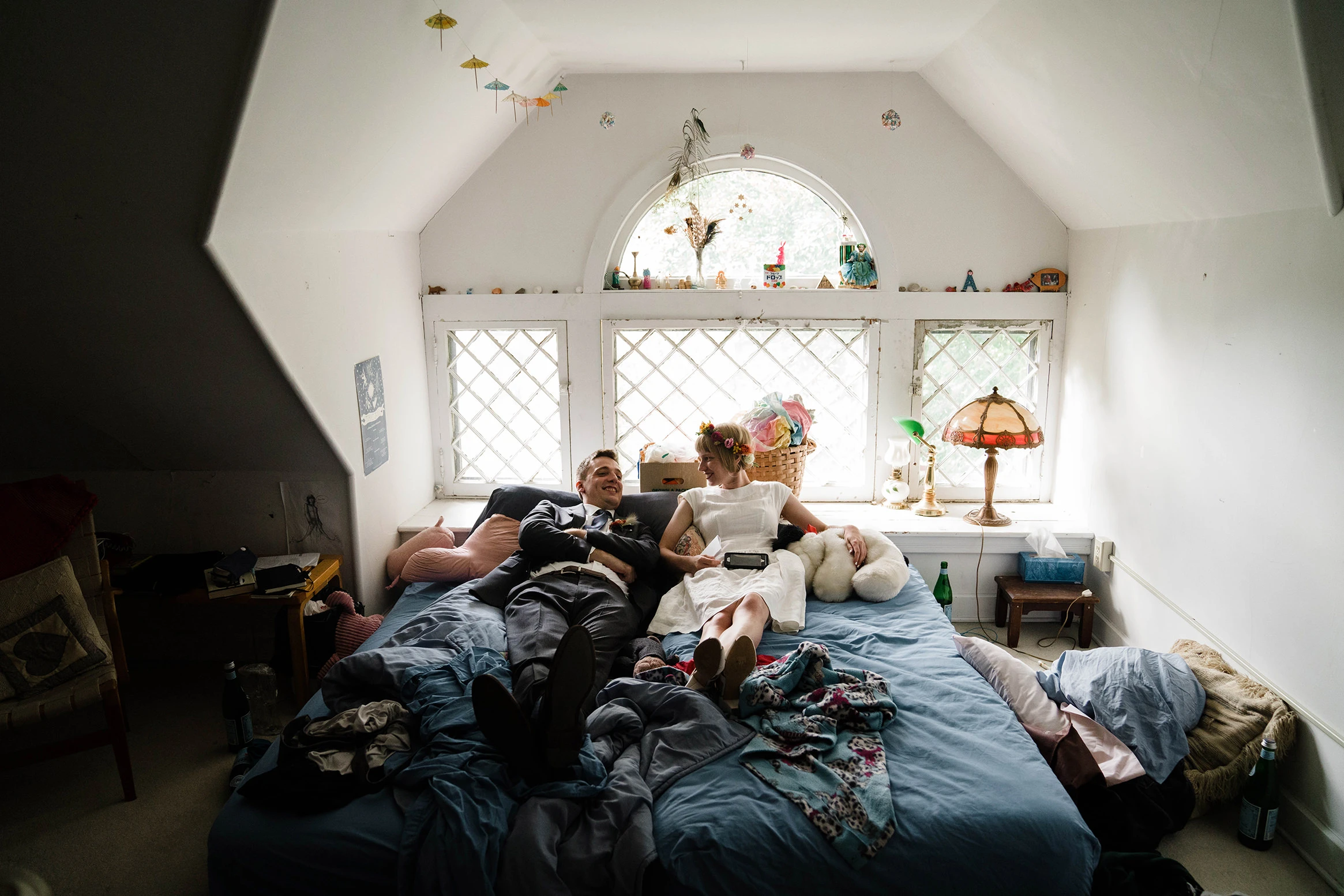 Friends lying on a bed in an attic room with a round window