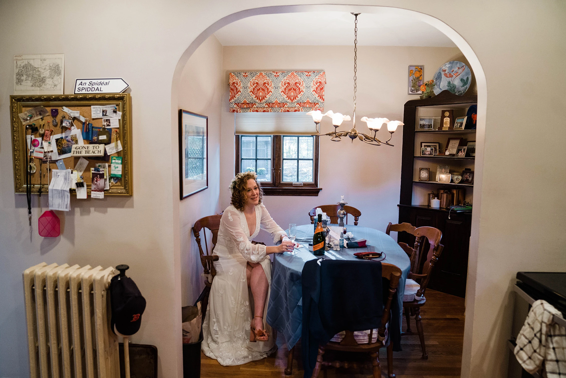 The bride sitting at a dining table seen through an arched doorway