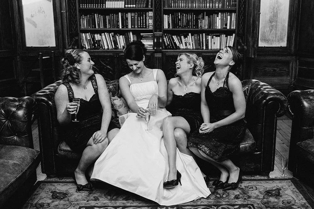 Bridesmaids and the bride on a leather sofa in a library