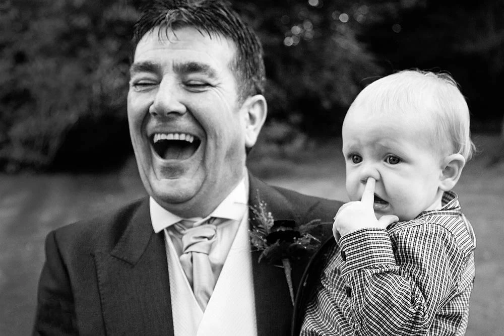 A man laughing as a toddler pokes his face