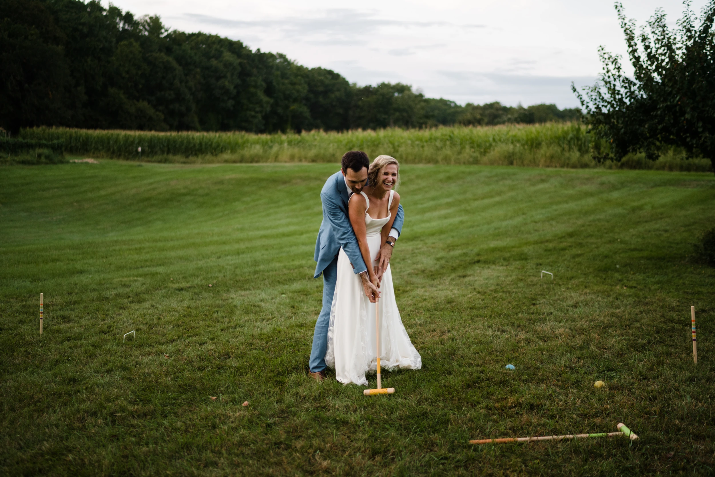 The couple holding each other on a wide lawn, a croquet hoop at their feet