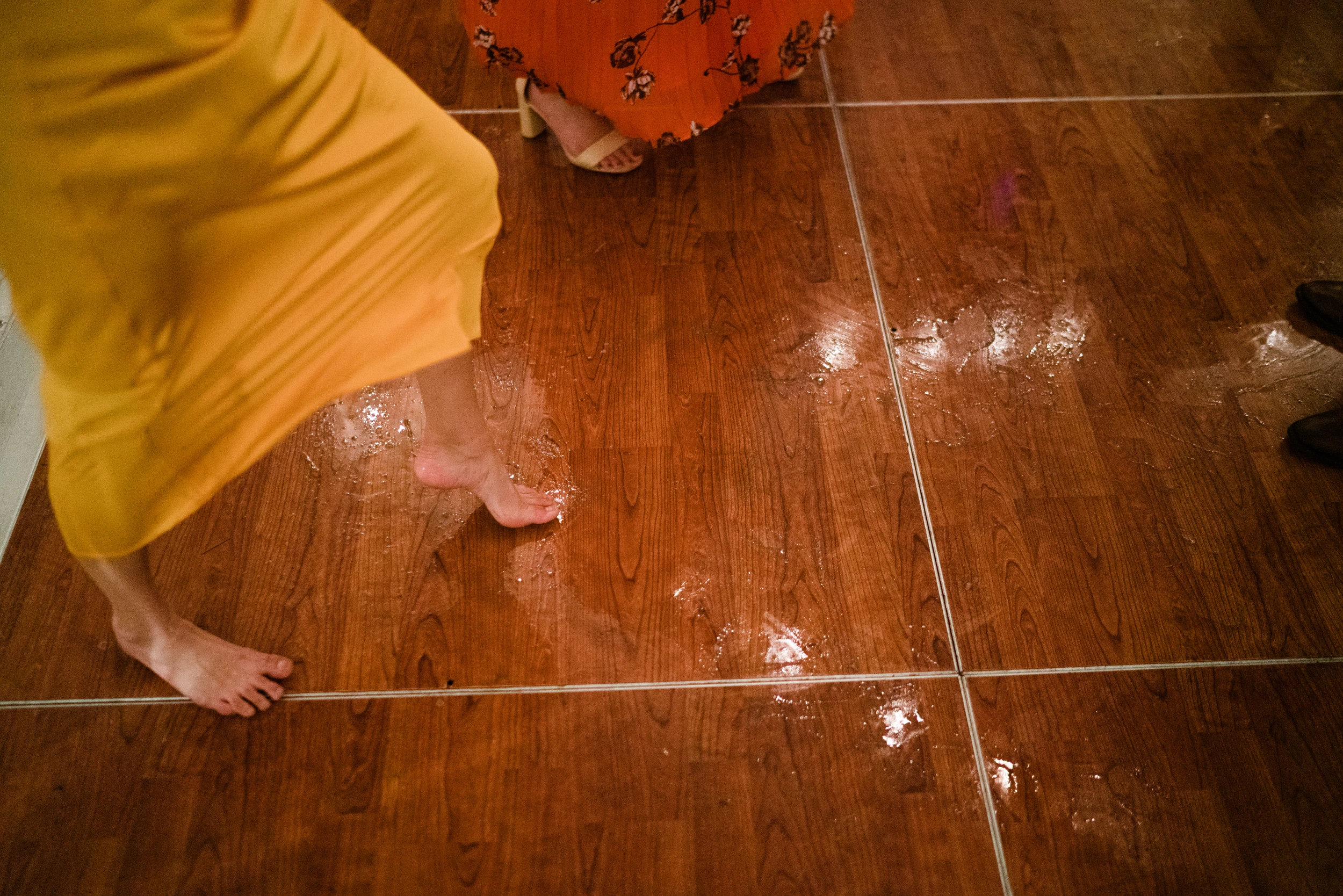 Bare feet and a yellow hem on a wooden dance floor
