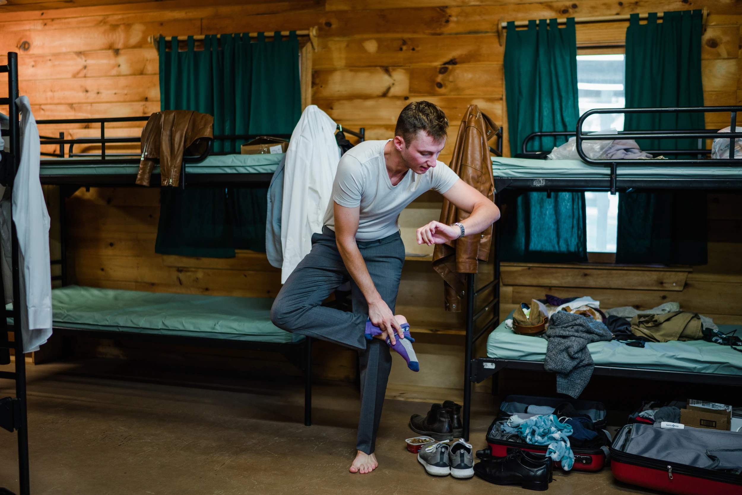 The groom dressing among bunk beds in a wooden cabin