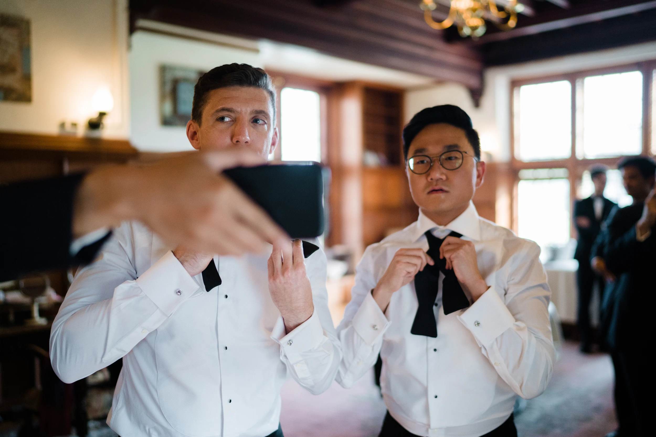 Two grooms fixing their bow ties side by side