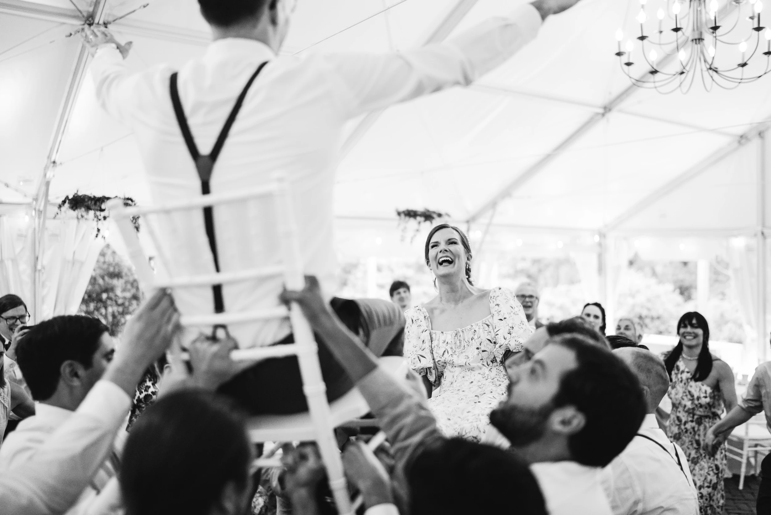 The bride lifted high on a chair under the tent