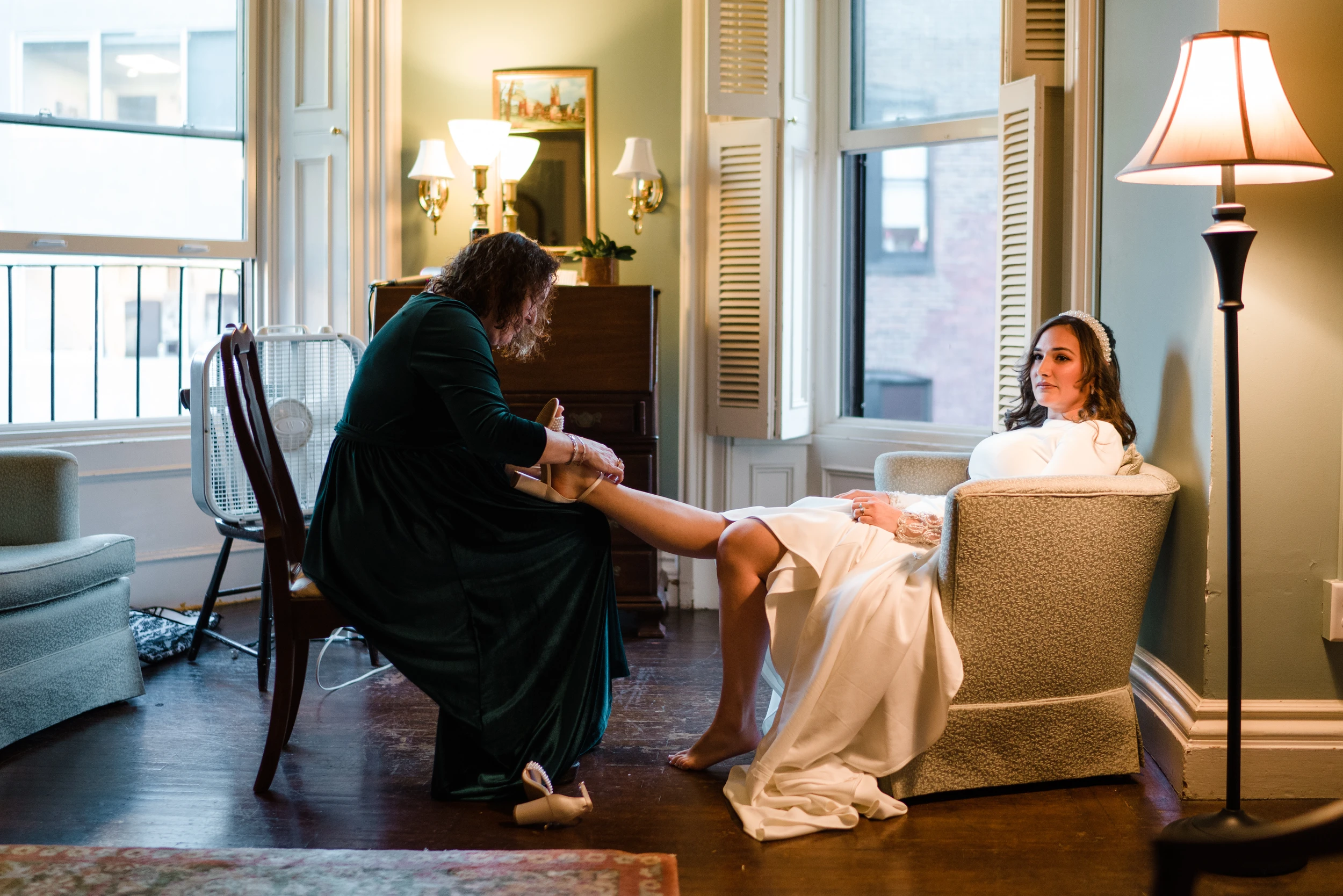 A woman helping the bride in an armchair by a lamp